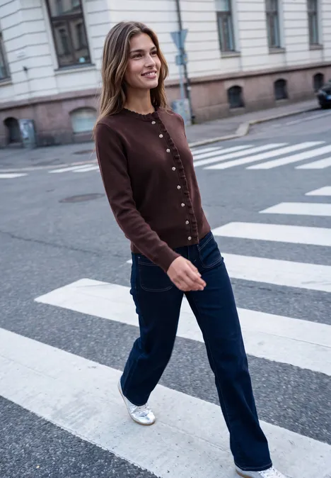 Cardigan mit Rundhals und Rüschendetails russet red Eine Frau in brauner Strickjacke und Jeans spaziert über einen Zebrastreifen in der Stadt.