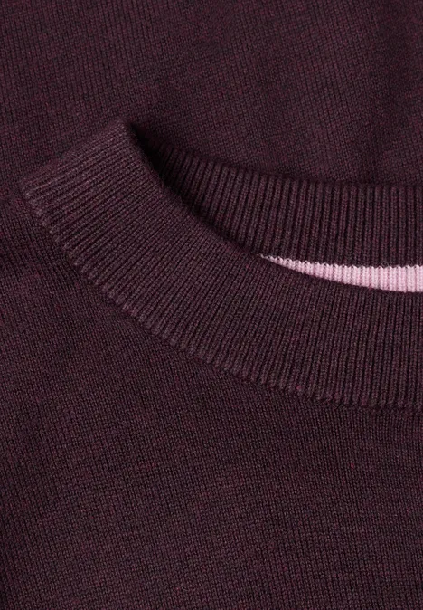 Nahaufnahme eines burgunderfarbenen Strickpullover-Kragens mit geripptem Abschluss und dezentem rosa Innenband.