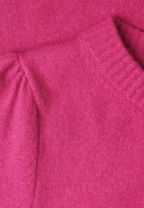 Nahaufnahme eines pinkfarbenen Strickpullover-Ärmels mit geripptem Kragen.