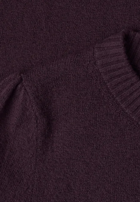 Gros plan sur un pull en maille bordeaux en tissu doux et duveteux.