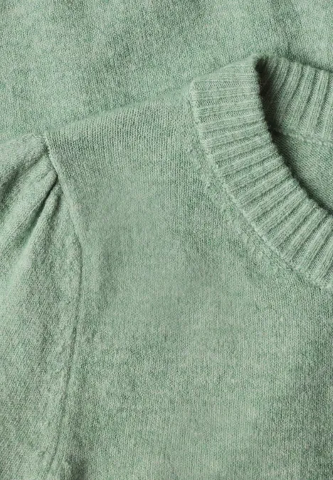 Nahaufnahme eines grünen Strickpullovers mit Rundhalsausschnitt und leichten Puffärmeln.