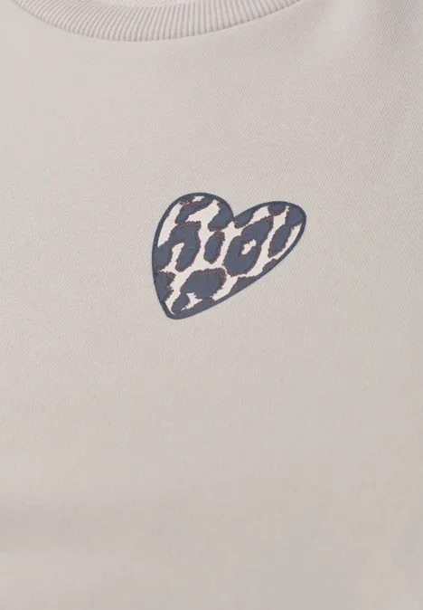 Beige T-Shirt mit kleinem, schwarz-weißem Leopardenherz-Aufdruck auf der Brust.