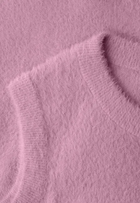 Nahaufnahme eines flauschigen rosa Strickoberteils mit weicher Textur.