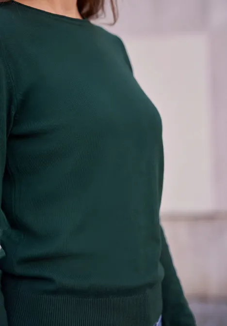 Eine Person trägt einen dunkelgrünen Pullover, nur Oberkörper sichtbar.