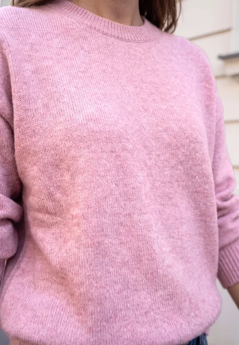 Nahaufnahme einer Person in einem rosafarbenen Pullover.