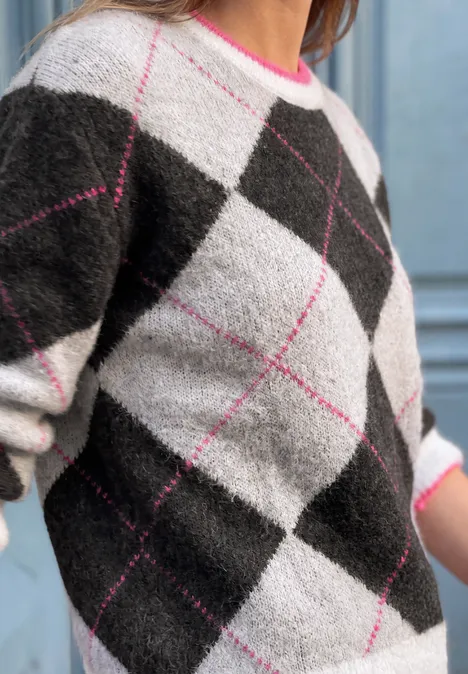Sweter z okrągłym dekoltem i wzorem argyle off white Zbliżenie na puszysty sweter w karo w czerni, bieli, szarości z różowymi akcentami.