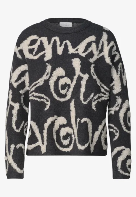Schwarzer Pullover mit beigen, geschwungenen Schriftzügen im Allover-Muster, lässiger Schnitt.