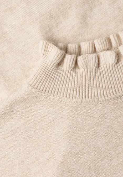 Gros plan d’un col côtelé de pull tricoté beige clair