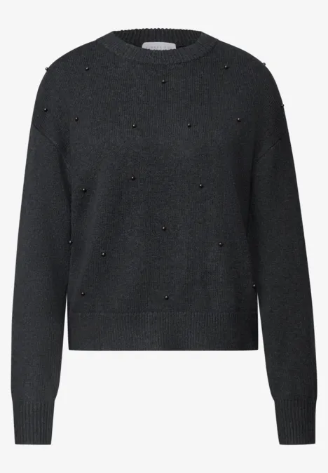 Schwarzer Pullover mit Rundausschnitt und kleinen goldenen Nieten als Akzente.