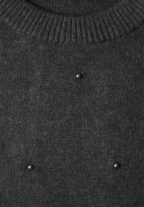 Dunkelgrauer Strickpullover mit geripptem Kragen und kleinen goldfarbenen Zierknöpfen.