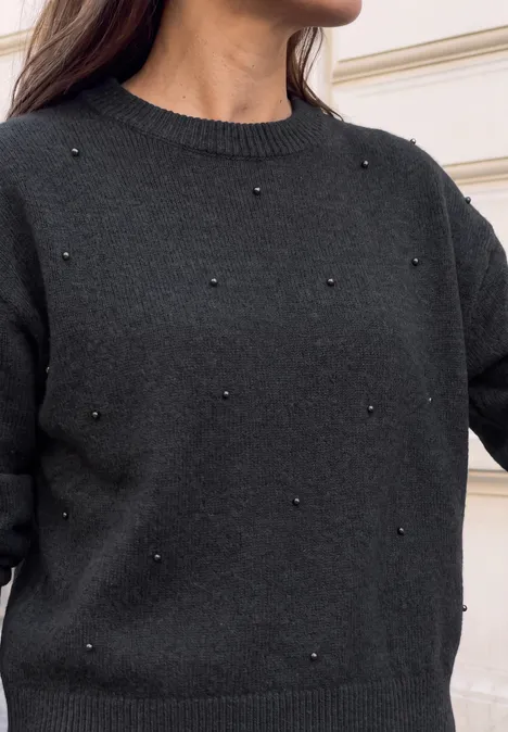 Eine Person trägt einen schwarzen Pullover mit kleinen Perlen.