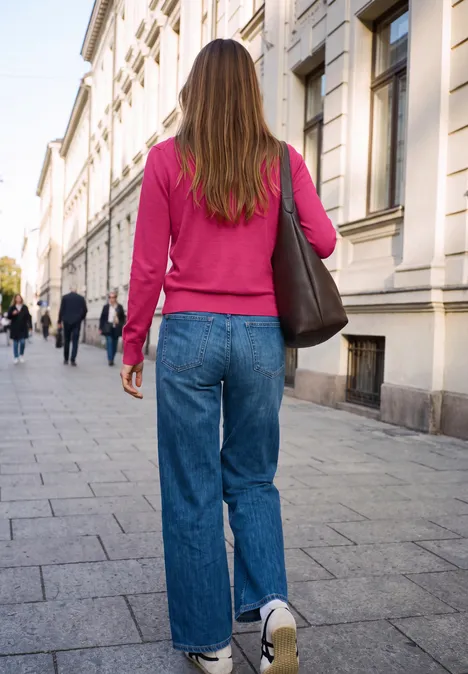 Trui met lange mouwen en sjaalkraag ruby raspberry Eine Frau in pinkem Hoodie, blauen Jeans und weißen Sneakern mit Schultertasche spaziert eine Stadtstraße entlang.
