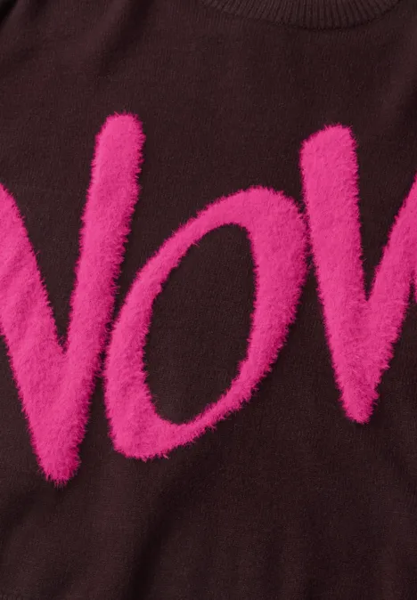 Brauner Pullover mit flauschigen, pinken Buchstaben "VOV" auf Brusthöhe.