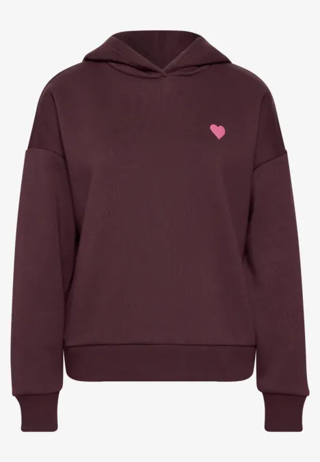 Ein weinroter Kapuzenpullover mit kleinem pinkem Herz-Logo auf der Brust.