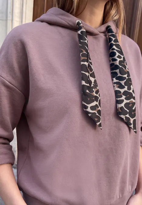 Sweat à capuche ample hazy rose Person trägt rosa Kapuzenpullover mit Leopardenmuster-Kordeln und hochgekrempelten Ärmeln.