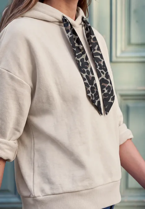 Beige Hoodie mit hochgekrempelten Ärmeln und leo-bedruckten Kapuzenbändern.