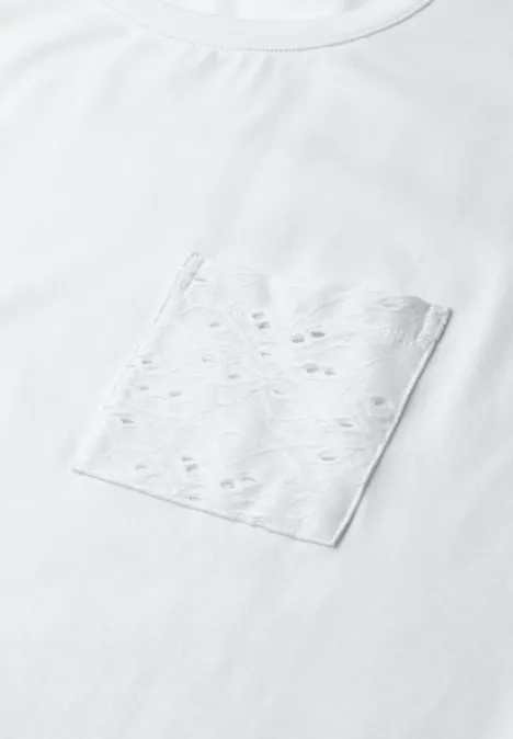 Weißes T-Shirt mit Brusttasche in hellem Ton und kleinen Lochmustern.
