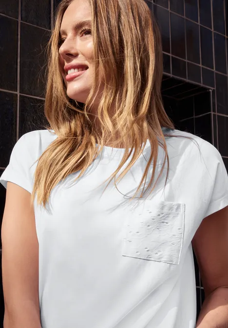 Mädchen mit weißem T-Shirt vor dunkler, gekachelter Fassade