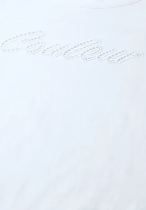 Nahaufnahme eines weißen T-Shirts mit dezentem, gepunktetem Schriftzug in geschwungener Schrift.