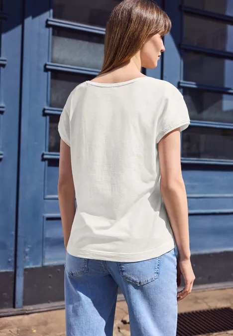 Vrouw van achteren in wit T-shirt en spijkerbroek voor een blauwe deur