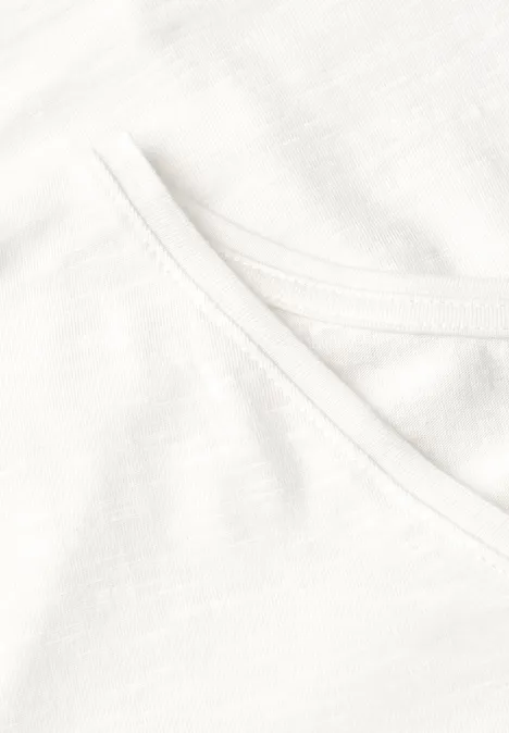 Close-up van een wit katoenen T-shirt met zichtbare stiknaden bij de hals.