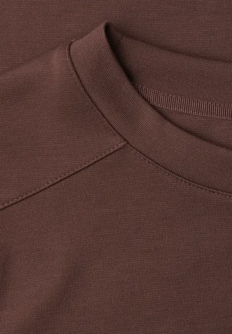 Gros plan d’un col de T-shirt brun foncé avec couture raglan