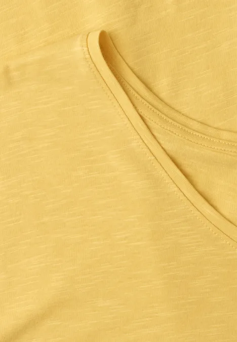 Close-up van een gele tanktop met geribbelde ronde hals.