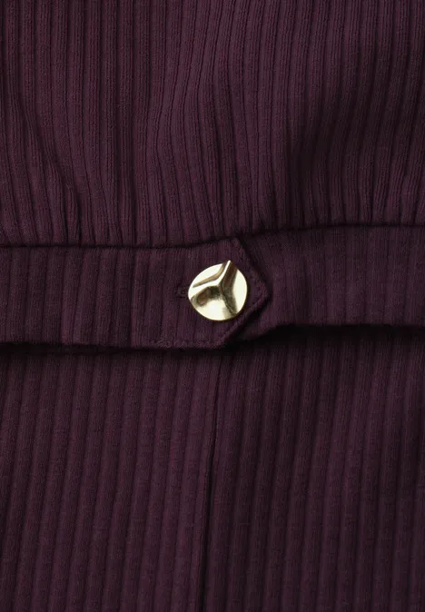 Donkerpaarse geribbelde stof met een goudkleurige driehoekige sierknop ter hoogte van de taille