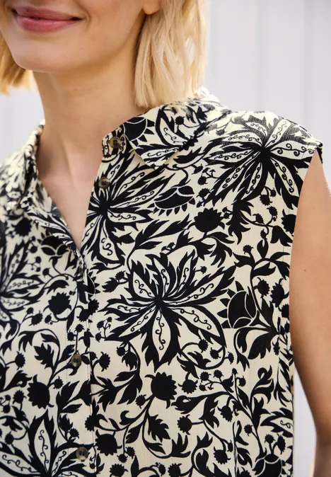 Frau mit ärmelloser Bluse in Schwarz-Weiß mit floralen Mustern