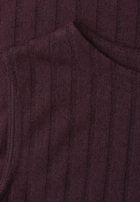 Nahaufnahme eines burgunderfarbenen, gerippten Strickstoffs mit angedeuteter Taschennaht.