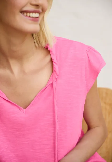 Dropped Shoulder Shirt mit Split Neck simply pink Eine lächelnde Frau trägt ein pinkfarbenes Oberteil mit V-Ausschnitt und Kordeldetails.