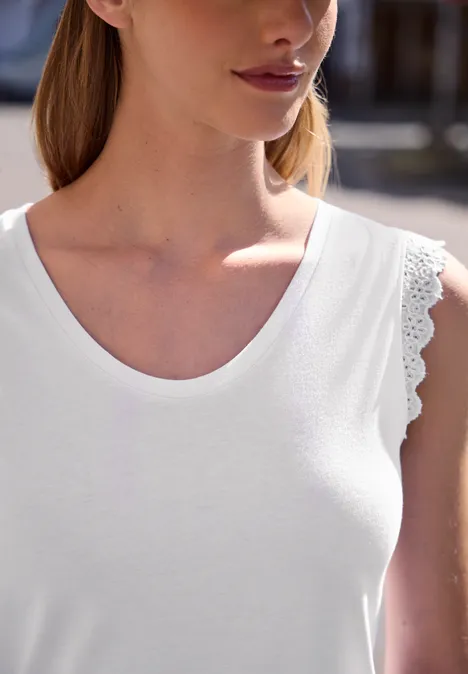 Top mit V-Neck und Rüschen White Nahaufnahme einer Person in weißem ärmellosem Oberteil mit Spitzenrand am Armloch.