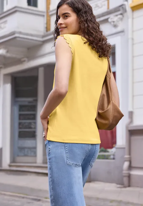 Top mit V-Neck und Rüschen snap yellow Frau in gelbem Top und Jeans mit brauner Tasche schlendert eine Straße entlang.