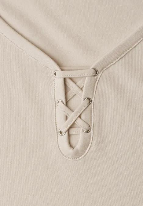 Beige Oberteil mit Schnürung am V-Ausschnitt.