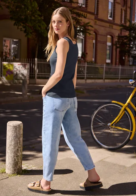 Top mit V-Neck und Bänderdetail maritime blue Frau in schwarzem Top und blauer Jeans, geht an gelbem Fahrrad vorbei.