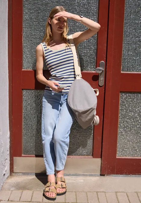 Top mit Rundhals und Rippstruktur optic blue Junge Frau in gestreiftem Tanktop und Jeans lehnt an Tür und hält eine Tasche.