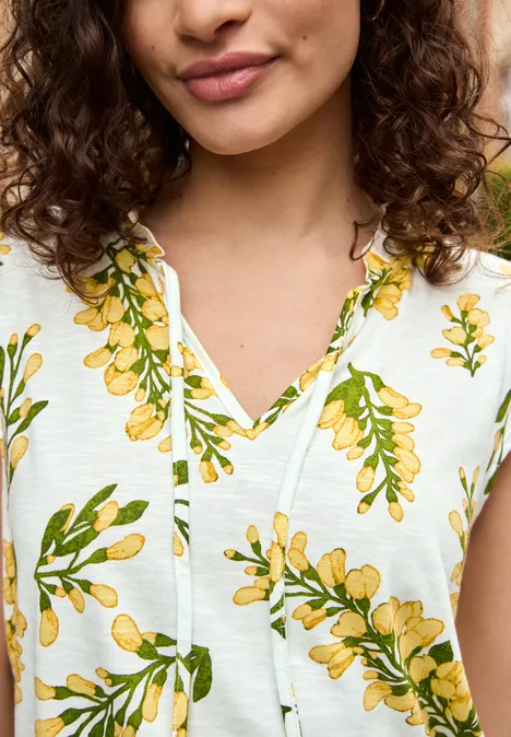 Close-up van vrouw in witte top met geel bloemenpatroon