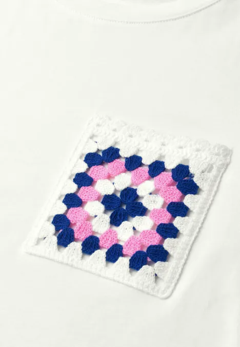 Weißes T-Shirt mit gehäkelter Tasche im Granny-Square-Muster in Pink, Blau und Weiß.