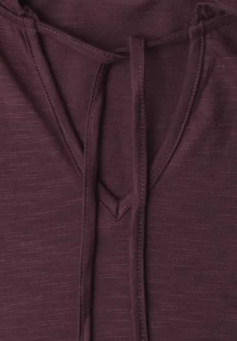 Close-up van een bordeaux hoodie met trekkoorden en fijne structuur.