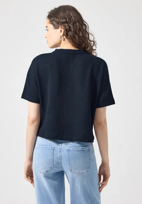 Kurzarm Jacke im Strick-Look mit Rundhals maritime blue Eine von hinten gezeigte Frau trägt ein dunkelblaues Kurzarmshirt und helle Jeans.