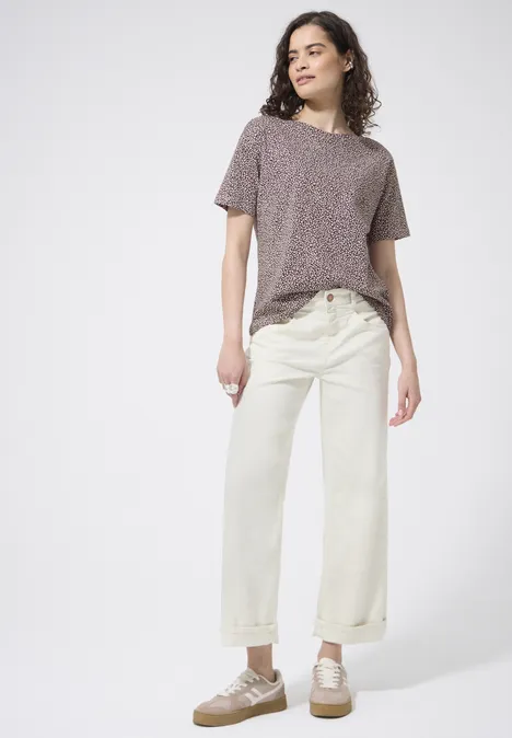 Een persoon draagt een loszittend grijs t-shirt, crème wijde jeans met hoge taille en beige veterschoenen.