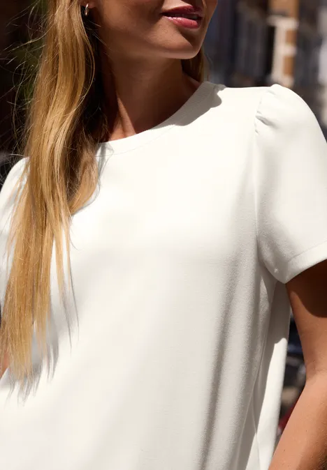 T-Shirt in Unifarbe mit Raffung off white Eine Frau im Sonnenlicht trägt eine weiße Bluse und lange blonde Haare.