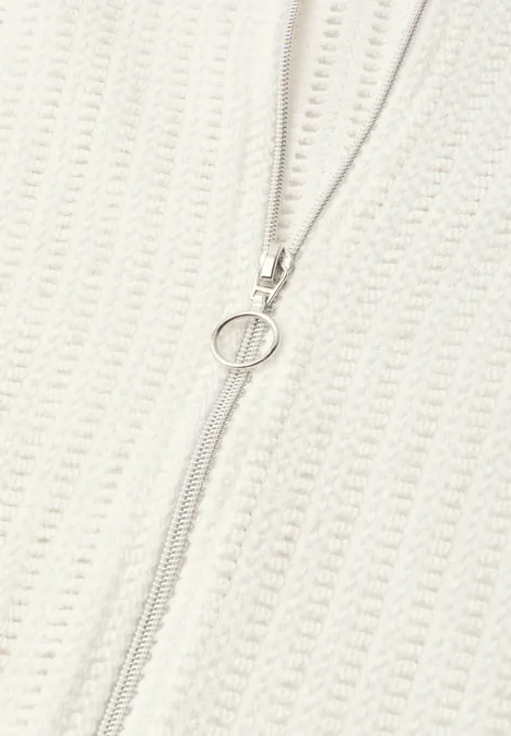 Jas met lange mouwen, structuur en ritssluiting off white Close-up van een crèmekleurige gebreide trui met een centrale rits en een ronde ritsklink.
