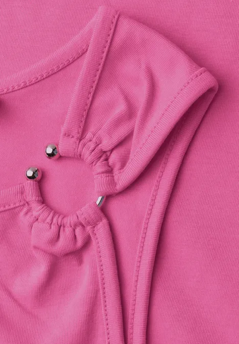 Asymmetrische top met ronde hals simply pink Close-up van roze stof met twee geplooide cirkels, verbonden door kleine zilverkleurige kraaltjes.