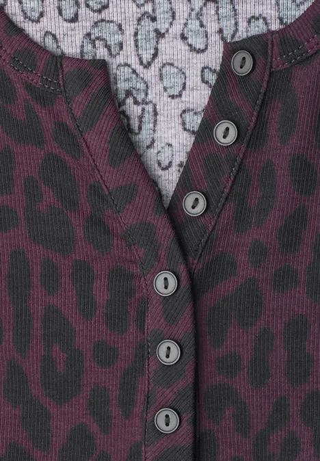 Nahaufnahme eines Pullovers mit violetter Leopardenmuster-Struktur und Knopfleiste