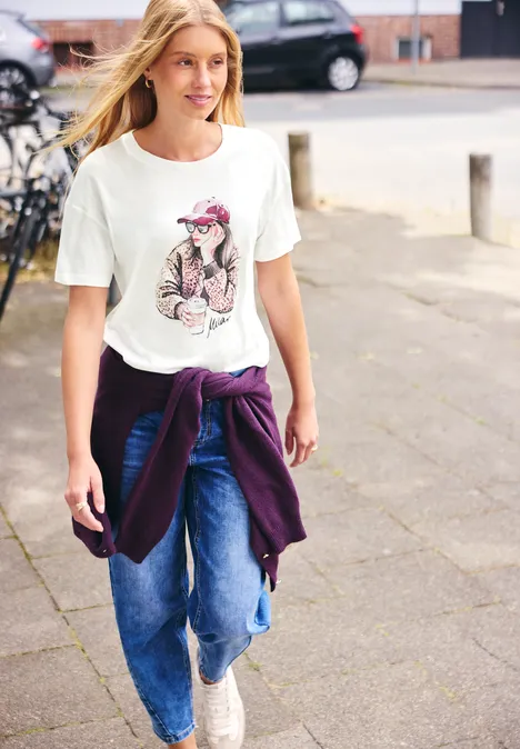 Shirt met ronde hals en opdruk off white Ein junges blondes Mädchen spaziert in Jeans, T-Shirt mit Hunde-Motiv und Sweatshirt um die Taille.