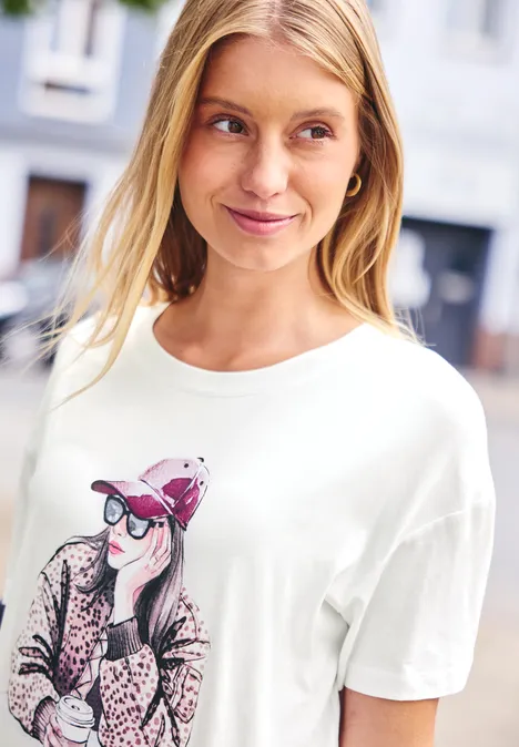 Shirt met ronde hals en opdruk off white Frau mit blondem Haar trägt weißes T-Shirt mit grafischem Motiv, unscharfer Stadthintergrund.