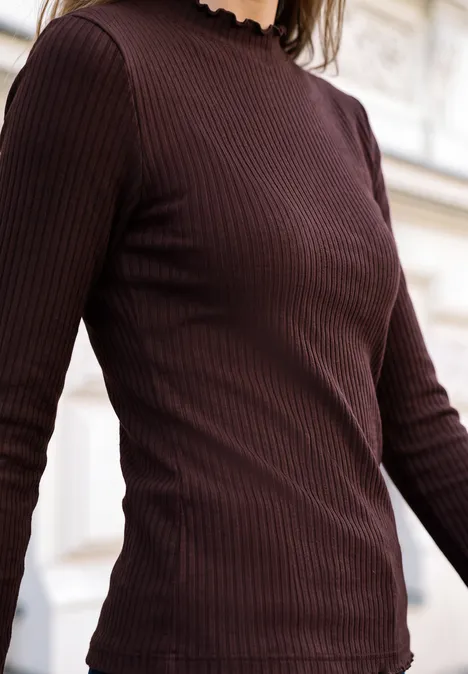 Langarm Shirt mit Turtle Neck russet red Eine Person mit braunem, langärmligem, geripptem Rollkragenpullover vor hellem Hintergrund.