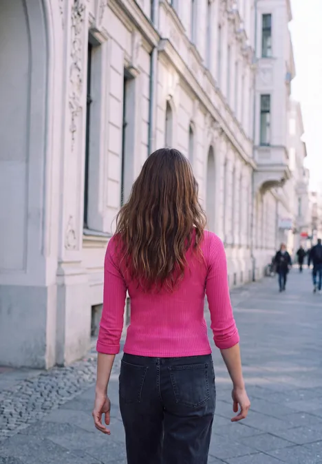 Langarm Shirt mit Turtle Neck ruby raspberry Eine Frau in pinkem Oberteil und Jeans geht eine breite Straße mit historischen Gebäuden entlang.