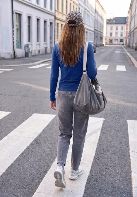 T-shirt basique uni à col rond starry blue Frau in blauem Oberteil und grauer Hose mit Tasche läuft über einen Zebrastreifen in einer ruhigen Stadtstraße.